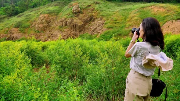 Young Asian female traveler is enjoying the beautiful scenery of the mountains and the green fields.