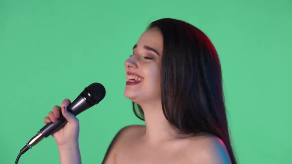 Portrait of Young Woman Illuminated By Blue Red Light Sings Song Into Microphone and Dances