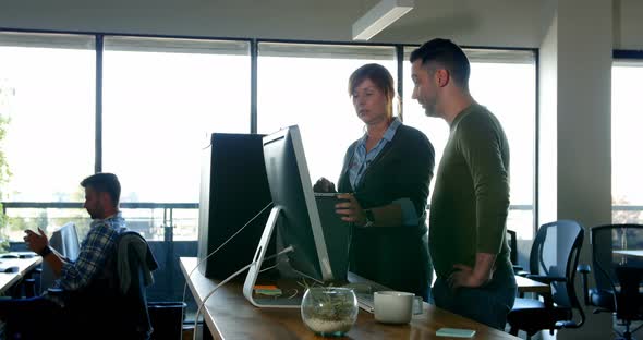 Executives discussing over laptop at desk 