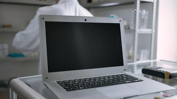 Laptop Screen in Pharmacy Ready for Tracking with Pharmacist at Background