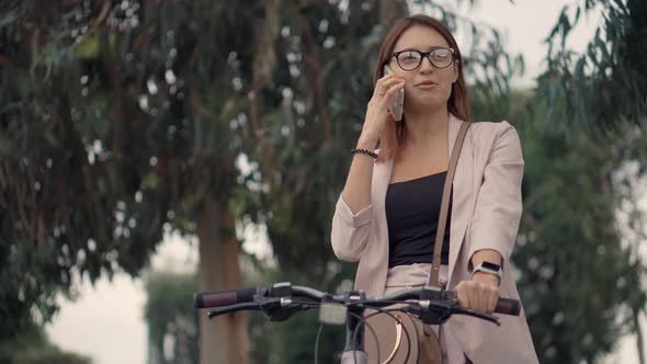 Woman Talking on Phone on a Bike Ride