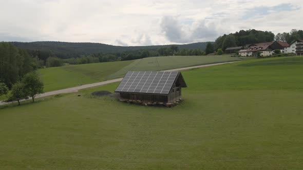 Sheep graze on a field near a barn with solar panels