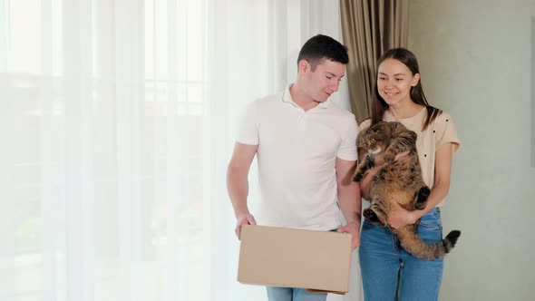 Husband and Wife Carry Box and Cute Cat to New House