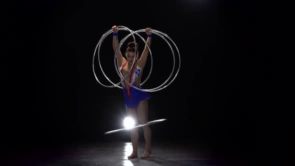 Gymnast in a Bright Outfit Twists a Hoop on Her Arm and Then on Her Leg