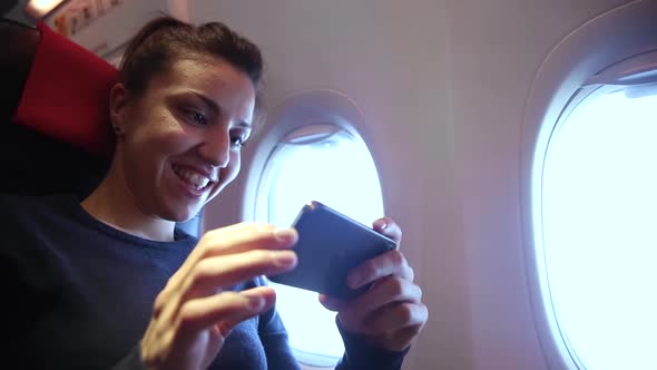 Woman on a plane using smartphone to take photos through the window