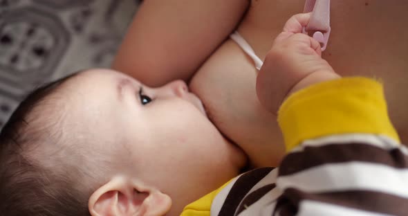 Mother Breastfeeding Her Newborn Baby on Sofa