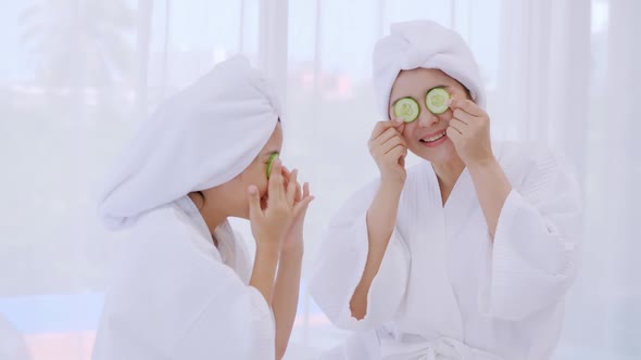 Mother with little daughter in bathrobes doing beauty treatment together in bedroom.