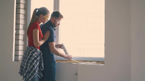 Man in Goggles with Wife Apply Spray Foam Insulation on Sill