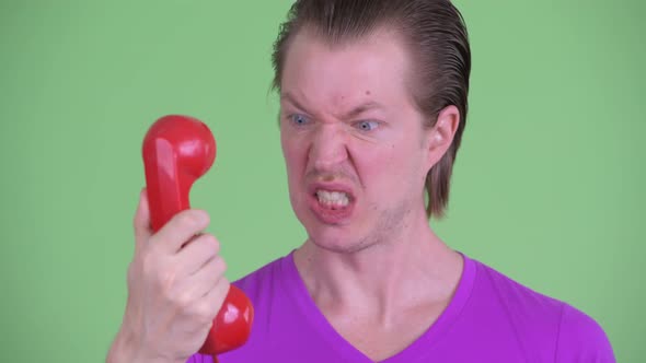 Face of Angry Young Man Shouting and Screaming at Old Telephone