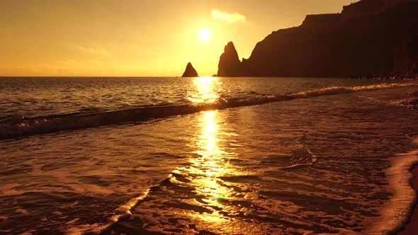 A Red Burning Sunset Over the Sea with Rocky Volcanic Cliff