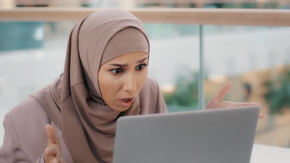 Young Worried Stressed Arab Businesswoman in Hijab Looking at Laptop Screen Feeling Shocked Annoyed