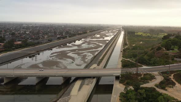 Panning aerial drone shot of a car driving over a bridge.