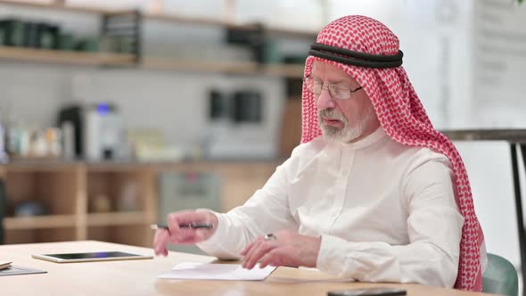 Senior Old Arab Businessman Trying To Write on Paper in Caf� 