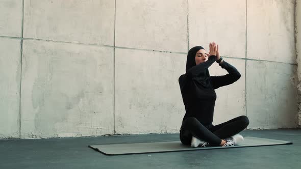 An arabian sports woman wearing a national hijab is doing yoga exercises