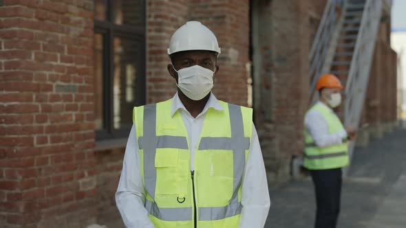 African American Builder in Mask Posing at Construction Site