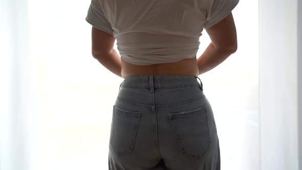 Back View Young Woman Buttons Up Jeans of a Smaller Size