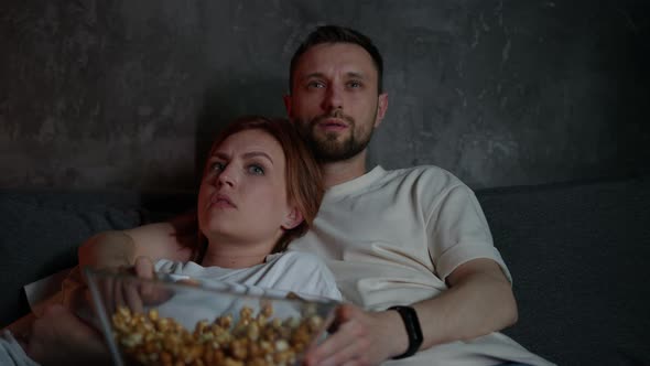 Closeup of a Married Couple Lying on the Couch and Watching Horror Movies