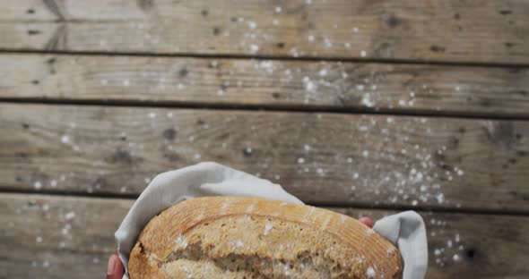 Video of bread in hands on wooden worktop seeing from above