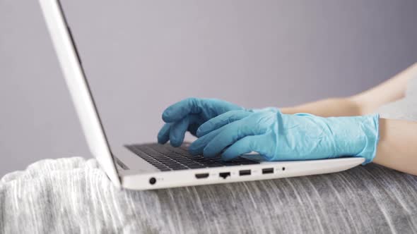 Woman Working with Laptop at Home in a Protective Suit and Gloves During the Quarantine Closeup