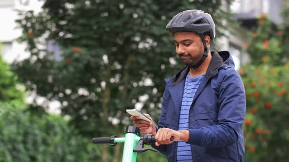 Man with Smartphone Riding Electric Scooter