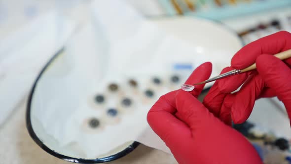 Glass eye prosthetic, close up. Ophthalmologist holds in hand eye prosthesis