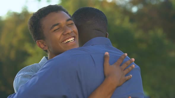 Smiling Afro-American Man Hugging Teenage Son, Feeling Happy and Proud, Trust