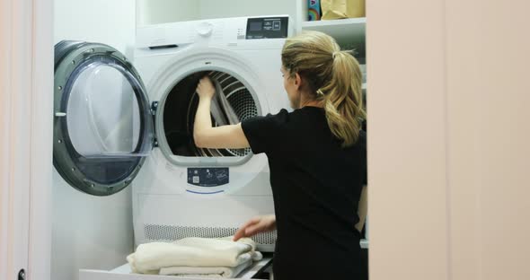 The Woman Takes Towels Out of the Washing Machine