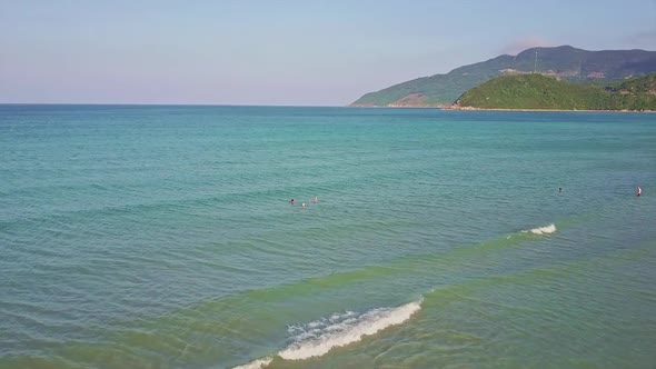 Drone Shows Azure Bay with People and Nice Beach Against Jungles