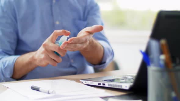 Man Using Hand Sanitizer at Home Office