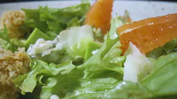 Salad with Grapefruit Green Lettuce Avocado Tuna Cheese on Gray Plate Rotating Close Up