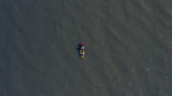 A man in a canoe fishing for food. Calm waters, Aerial, slow movement, top view. River over capital