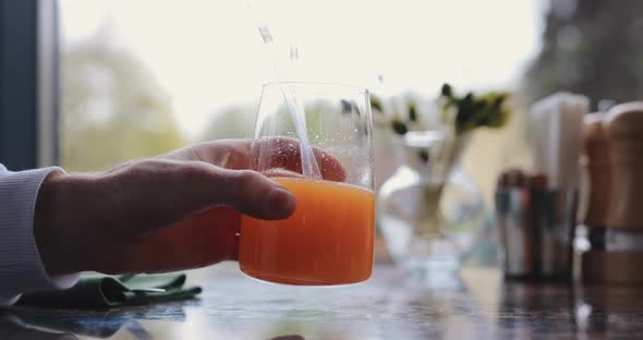 Male Hand Holding Juice in Glass and Shake Up It