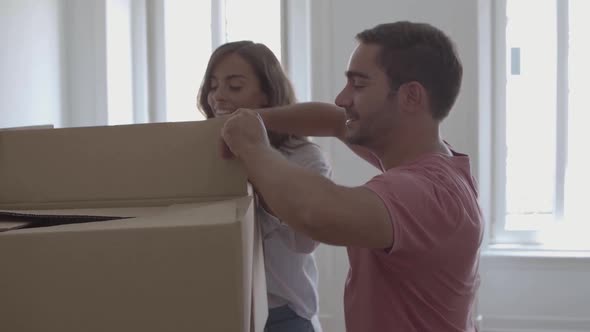 Young Couple Opening Box with Pillows and Smiling