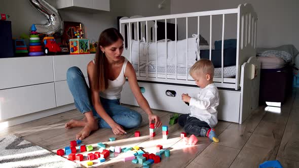 Little Cute Boy with His Mother Play with Toys at Home