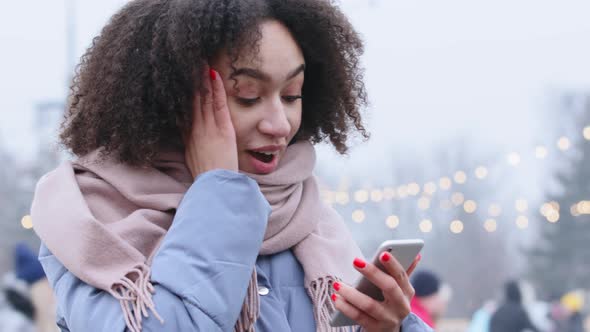 Portrait of Afro American Millennial Girl Standing Outdoors in Cold Weather Holds Mobile Phone in