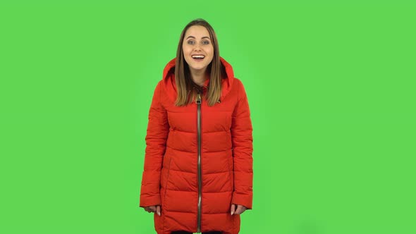 Lovely Girl in a Red Down Jacket Is Waving Hand and Showing Gesture Come Here. Green Screen