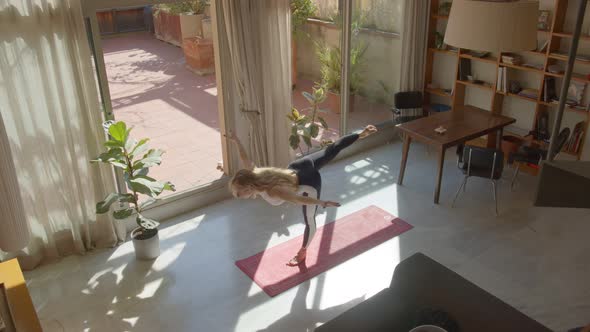 Long Hair Attractive Slim Caucasian Woman in a Sports Bra and Leggins Doing Yoga Poses at Home