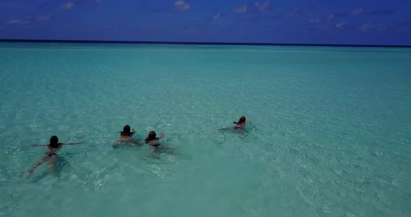 Pretty smiling girls travelling by the sea at the beach on sunny blue and white sand background 4K