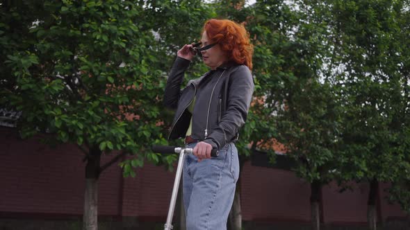 Side View Confident Redhead Beautiful Retro Woman in Leather Jacket and Denim Jeans Putting on