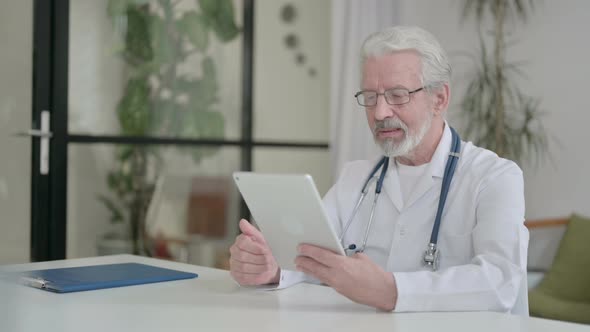 Senior Old Doctor Making Video Call on Tablet in Clinic