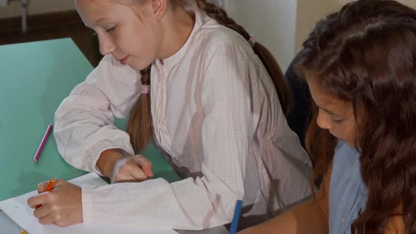 Two Little Schoolgirls Coloring Together During Art Class