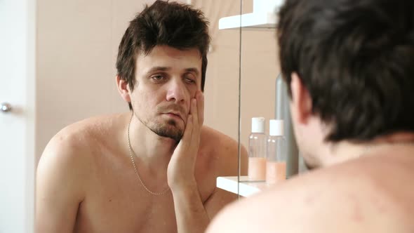 Tired Man Who Has Just Woken Up Looks at His Reflection in the Mirror Slaps His Cheek