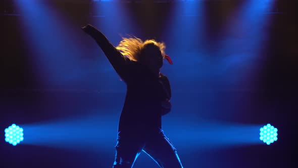 Silhouette of a Talented Young Girl Hip Hop Dancer. Hip Hop Street Dance on a Stage in Dark Studio