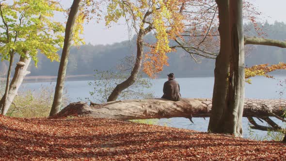 Lonely Man in a Leather Jacket Looks at an Autumnal Lake