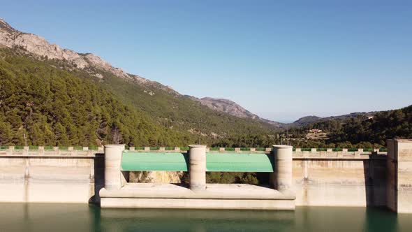 Guadalest water reservoir in hills and mountains overgrown with green forests on a sunny day - Spain