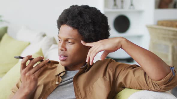 Happy african american man using smartphone at home