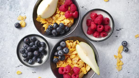 Golden Cornflakes with Fresh Fruits of Raspberries, Blueberries and Pear in Ceramic Bowl