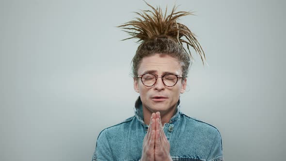 Stylish Man Praying in Studio. Serious Guy Holding Hands in Prayer Position