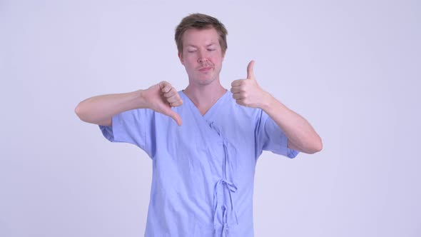 Confused Young Man Patient Choosing Between Thumbs Up and Thumbs Down