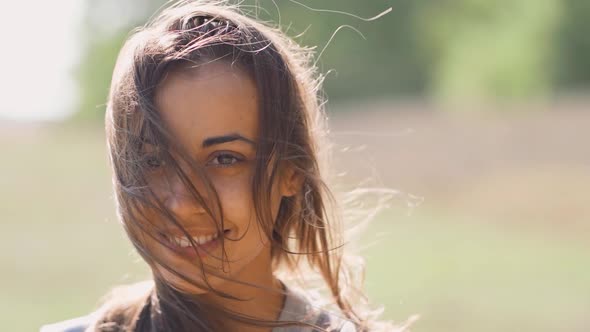 Calm Pretty Smiling Woman Outdoors with Blowing Hair at Sunny Autumn Day